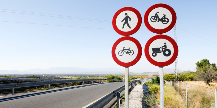 Kırsal bir yolda yayalara, motosikletlere, bisikletlere ve traktörlere yasak anlamına gelen dört trafik levhası yer alıyor.