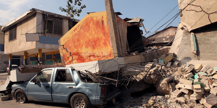 Deprem sonrası yıkılan bina enkazı altında kalan otomobil