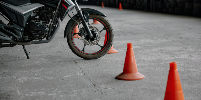 Bir motosiklet, eğitim alanında trafik konileri arasında manevra yapıyor.